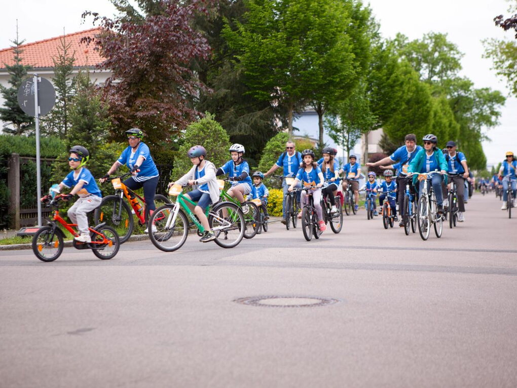 Eine Gruppe radfahrender Kinder und Erwachsener biegt an einer Kreuzung nach rechts ab.