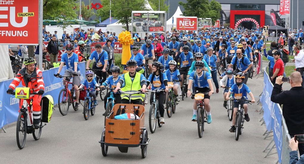 Eine große Gruppe Erwachsene und Kinder startet beim Fahrradfest.