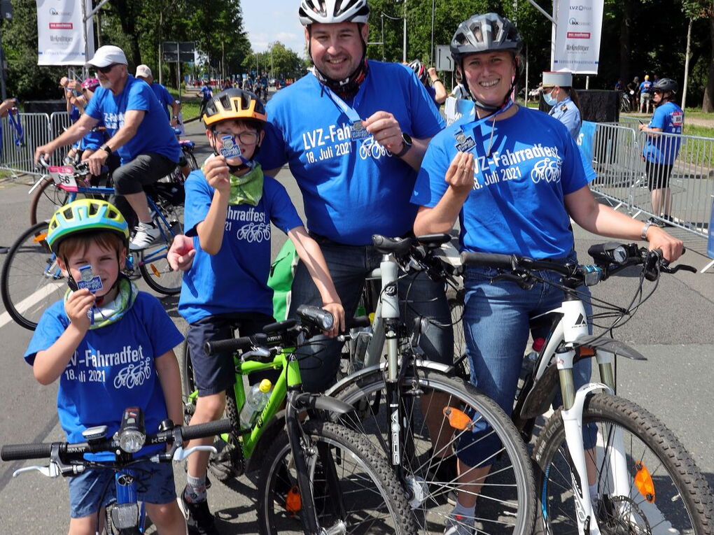 Eine Familie mit Mutter, Vater und zwei Kindern mit Fahrrädern halten stollz ihre Fahrradfest-Medaillen in die Kamera.