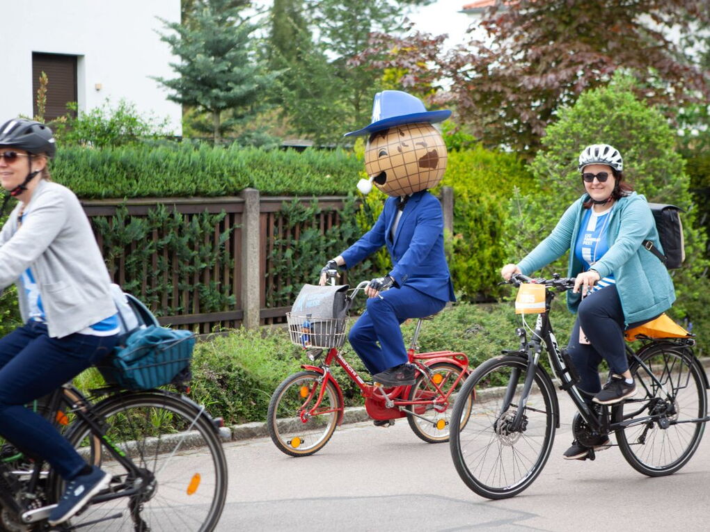 Das Maskottchen der Leipziger Messe radelt auf einem Klapprad zwischen Teilnehmenden des Fahrradfestes