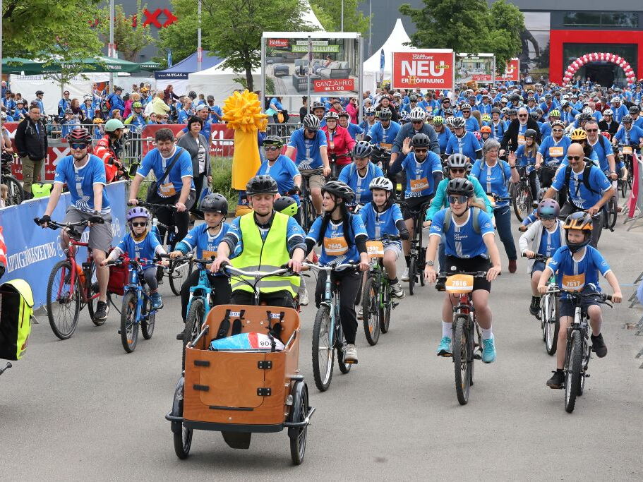 Eine große Gruppe Erwachsene und Kinder startet beim Fahrradfest.