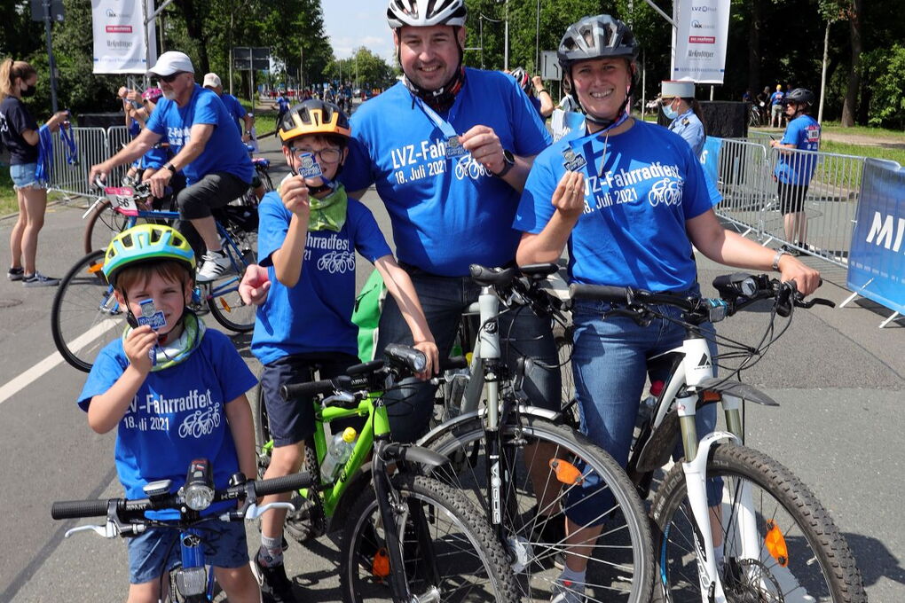 Eine Familie mit Mutter, Vater und zwei Kindern mit Fahrrädern halten stollz ihre Fahrradfest-Medaillen in die Kamera.