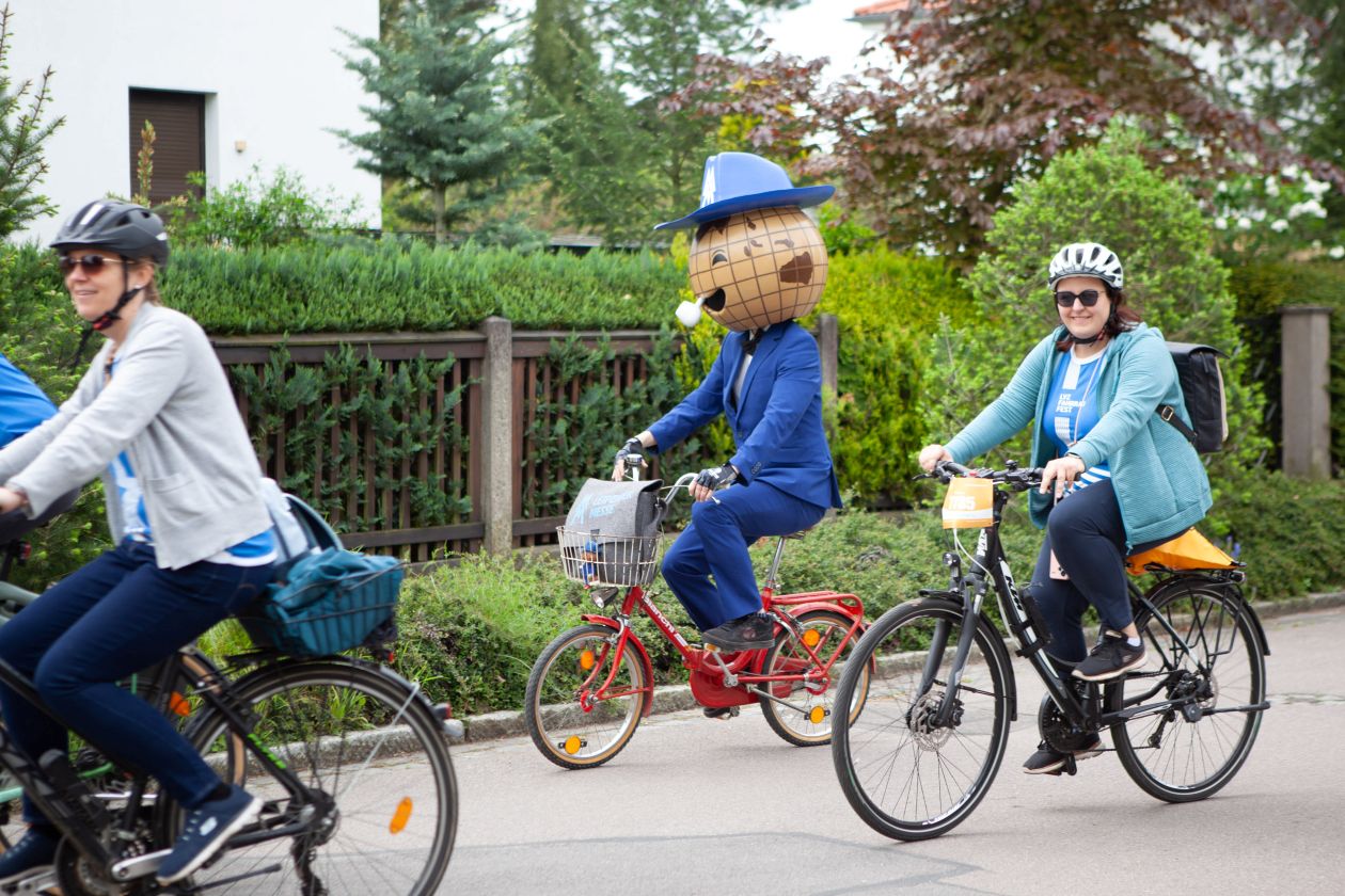 Das Maskottchen der Leipziger Messe radelt auf einem Klapprad zwischen Teilnehmenden des Fahrradfestes