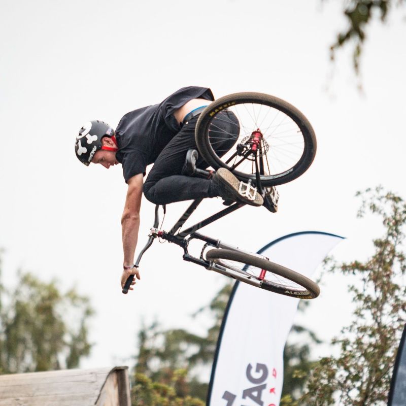 Ein junger Mann vollführt auf einem Fahrrad einen Stunt in der Luft.